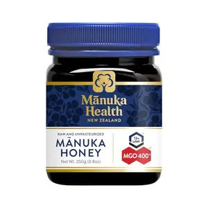 Manuka Health UMF 13+ honey jar with a wooden honey dipper lifted out, honey dripping