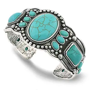Antique silver-toned cuff bracelet with a heart-shaped turquoise stone on a wood background