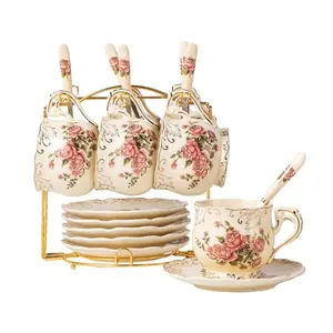 Six pink rose teacups with saucers displayed on a golden metal rack