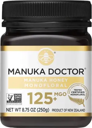 Manuka Doctor MGO 125+ honey jar with a spoonful of golden honey being added to a cup of tea