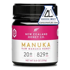 Jar of New Zealand Honey Co. Raw Manuka Honey UMF 20+ with dark amber honey on a wooden spoon