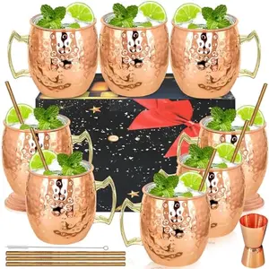 Eight hammered copper mugs arranged with straws and a jigger on a bar counter