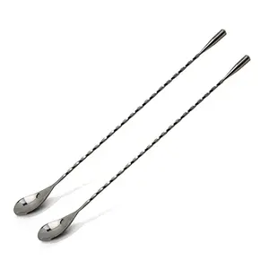 Two The Art of Craft 12.5-inch bar spoons with weighted teardrop ends on a cocktail napkin