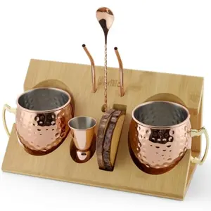 Two copper mugs with accessories displayed on a natural bamboo stand