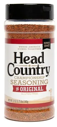 Head Country Championship Seasoning bottle on a wooden table next to grilled meats