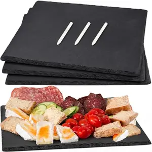 Four rectangular black slate cheese boards with chalk on wooden table