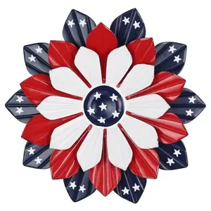A red, white, and blue metal flower wall art with star accents hanging on a wooden fence