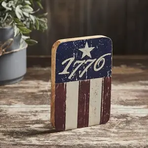 Vintage 1776 wooden sign with distressed flag stripes leaning on a fireplace mantle