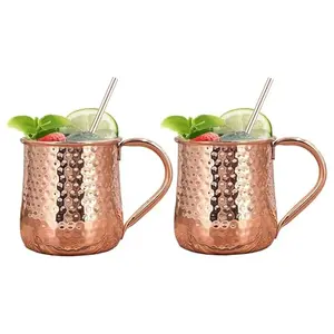 Two sleek hammered copper mugs with golden handles and straws on a marble surface