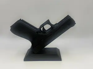 Black 3D-printed pistol-shaped business card holder with a few business cards inserted in the barrel area