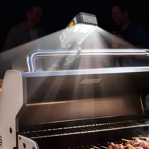 Goldusk grill light mounted on a grill handle illuminating the cooking surface