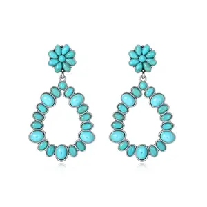 Pair of handmade turquoise drop earrings with silver hooks on a wooden surface