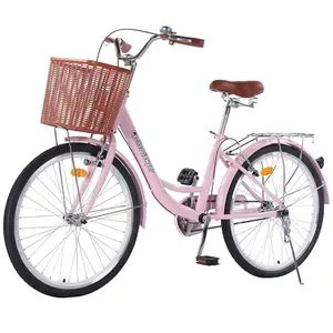 Light pink Cyclist Sawyer cruiser bike with rattan basket on a sunny beach road