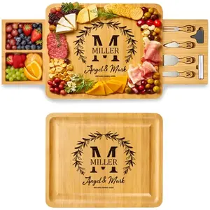 Personalized bamboo charcuterie board set with drawer and cheese knives on granite countertop